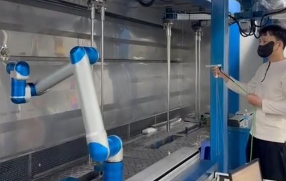 Kỹ thuật viên dắt tay cobot để dạy quỹ đạo phun